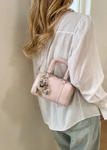 Close-up of pink pillow handbag with fur pompom and pearl charms for women