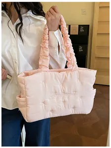 Detail of light pink quilted tote bag with bow embroidery and ruffled handles