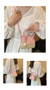 Detail of mini woven straw bag with pink leather lid and starfish shell charms