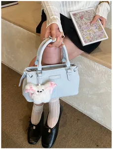 Detail of light blue faux leather bucket bag with a plush dog charm and metal buckle