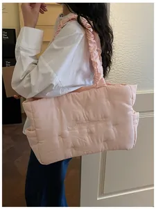 Detail of pink quilted tote bag with ruffled strap and delicate butterfly embroidery