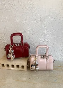 Detail of burgundy and pink leather boston bags with decorative charms on stone bases