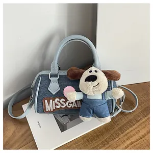 Detail of blue denim Boston bag featuring Missgail embroidery and plush dog charm