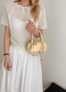 Detail shot of a light yellow leather handbag featuring a smooth texture and logo debossing
