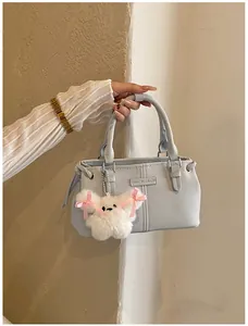 Detail of light blue bucket bag featuring vertical stitching and a plush doll charm