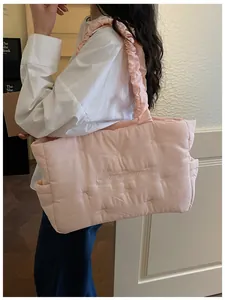 Detail of light pink quilted nylon tote bag featuring bow patterns and letter embroidery
