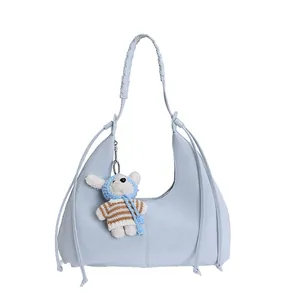Détail du sac hobo croissant bleu clair avec poignée tressée et breloque ours en peluche