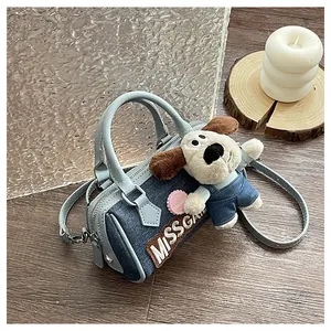 Detail of blue denim Boston bag with embroidered text and cute plush puppy charm