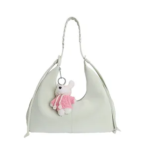 Détail du sac à main vert clair avec texture en cuir et pendentif ours en peluche mignon