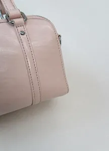 Detail of light pink faux leather bag showing glossy texture and silver hardware