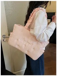 Detail of pink quilted nylon tote bag with ruffle shoulder strap and cloud texture