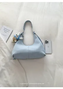 Sac hobo bleu clair avec bandoulière tressée et pendentif lapin sur fond de tissu doux