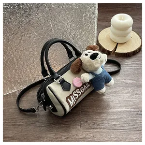 Close-up of cream canvas Boston bag with plush puppy charm and MISSGAIL lettering