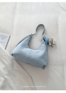 Détail d'un sac hobo bleu clair avec poignée tressée et un petit pendentif lapin au crochet