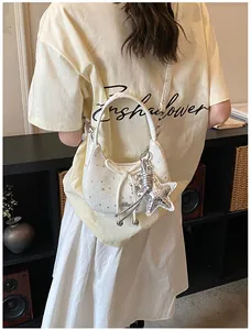 Detail van witte halvemaanvormige tas met sterprint en grote metalen ster-hanger