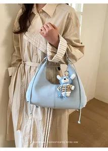 Détail du sac hobo bleu clair avec glands à cordon et un charmant porte-clés ours