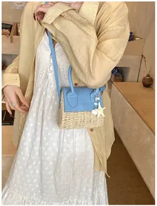 Straw mini crossbody bag with blue flap and starfish pendant shown on a model