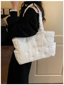 Detail of white quilted nylon tote bag featuring pink bow embroidery and ruffled handles