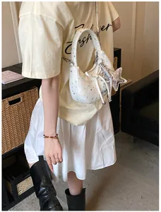 Detail van de witte crossbodytas met sterrenpatroon en zilveren sterrenhanger