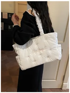 Detail of white quilted tote bag featuring pink ribbon bows and ruched shoulder strap