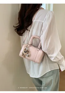 Detail of pink faux leather boston bag with metal heart pendant and plush charm