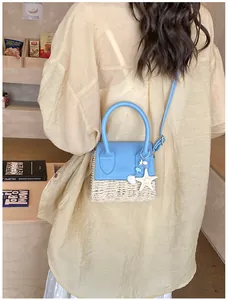 Detail view of woven straw shoulder bag with blue leather flap and sea star pendant charms