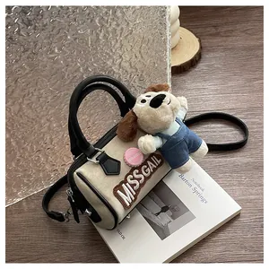 Detail of beige canvas Boston bag featuring black leather trim and cute puppy plush charm