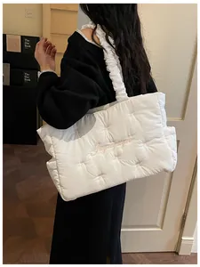 Detail of white quilted nylon tote bag featuring pink bow embroidery and ruffled strap