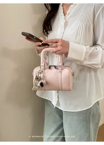 Close-up of pink pillow bag with pearl charm and fuzzy pompom accessory
