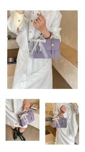Detailed view of purple leather handbag featuring lace bow and pearl charm ornament