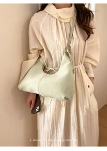 Gros plan du sac hobo vert clair au fini lisse avec une robe plissée beige élégante