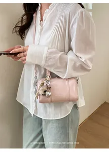 Detail of light pink mini pillow bag featuring silver heart charm and leopard pompom