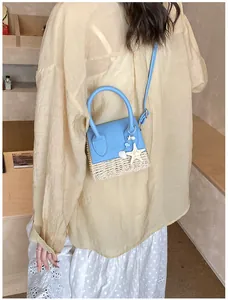 Close-up of mini straw crossbody bag with starfish pendant and blue leather trim