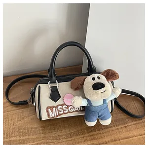 Detail of cream canvas Boston bag with black leather straps and plush puppy charm