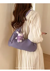 Détail du sac hobo plissé violet avec un pendentif lapin en peluche blanc sur l'anse