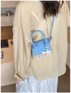Detail of mini straw bag with ocean charms and blue leather stitching shown on model