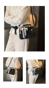 Detail of black vintage leather handbag with pearl lace charm and gold logo lettering
