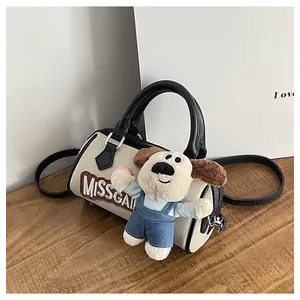Detail of cream canvas Boston bag with black handles and a cute puppy plush charm