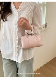 Detail of light pink patent leather boston bag with silver hardware and logo embossing