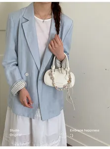 Detail view of white minimalist crossbody bag with beaded pendant and brand lettering