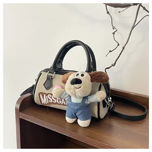 Detail of beige canvas Boston bag with black leather trim and cute puppy plush charm