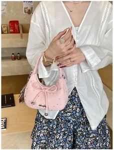 Roze hobo-tas met strik, zilveren sterren en metalen bedel in een lifestyle-omgeving