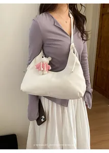 Détail du sac à bandoulière blanc en croissant avec couture minimaliste et charm d'ours
