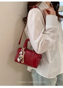Detailed view of a red minimalist pillow bag with heart charm shown on a model