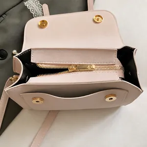 Detail view of pink square bag showing gold hardware, magnetic clasp and black lining