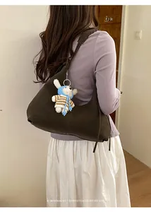 Détail du sac demi-lune en cuir marron foncé avec un petit pendentif lapin tricoté