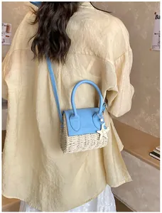 Detail showing mini crossbody straw bag with blue leather flap and starfish charm pendant