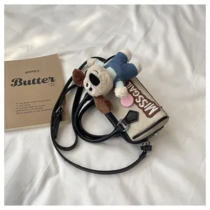 Top view of cream canvas Boston bag with black trim and a plush puppy charm attachment