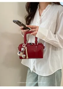 Detail of red leather Boston bag with silver heart charm and leopard pompom accessory