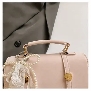 Close-up of pink square handbag featuring pearl beads, lace ribbon and gold metal hardware